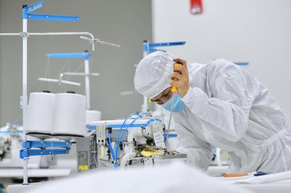 在位于晉江的福建海峽石墨烯產(chǎn)業(yè)技術(shù)研究院的無菌實驗室，技術(shù)人員在調(diào)試剛剛送達的防護服生產(chǎn)設(shè)備。新華社記者姜克紅攝